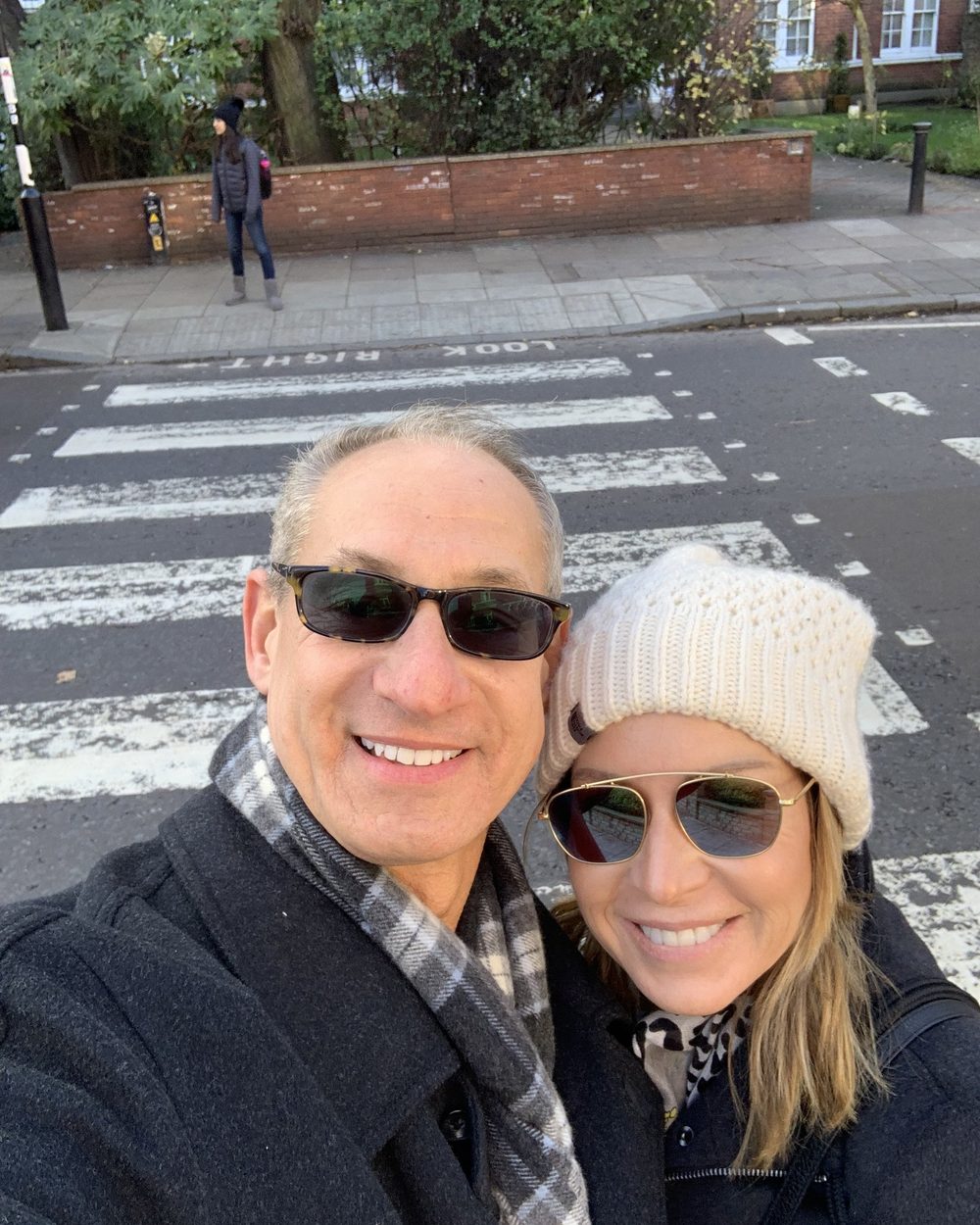 Ben and Loree in winter coats and sunglasses on the Abbey Road crosswalk in London